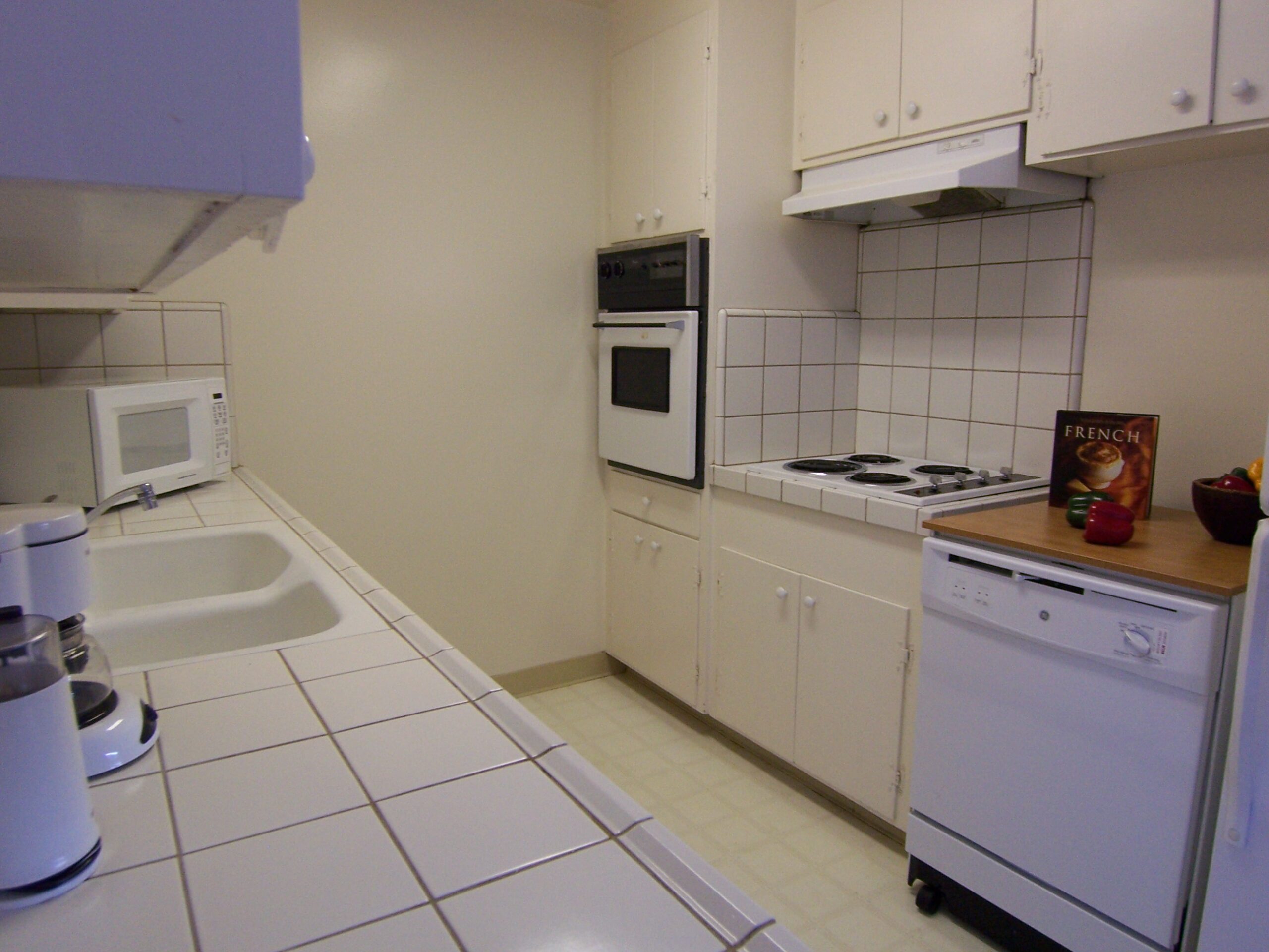 A kitchen with white tile and white appliances.