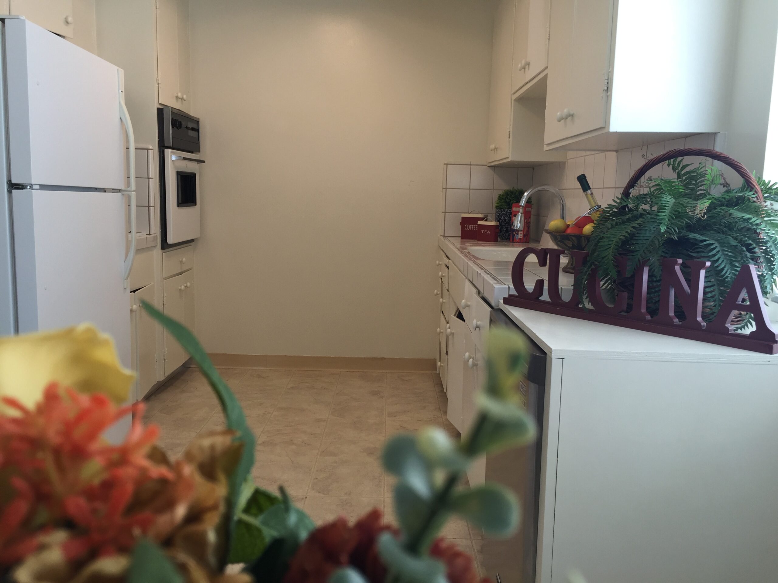 A kitchen with white cabinets and flowers in the center.