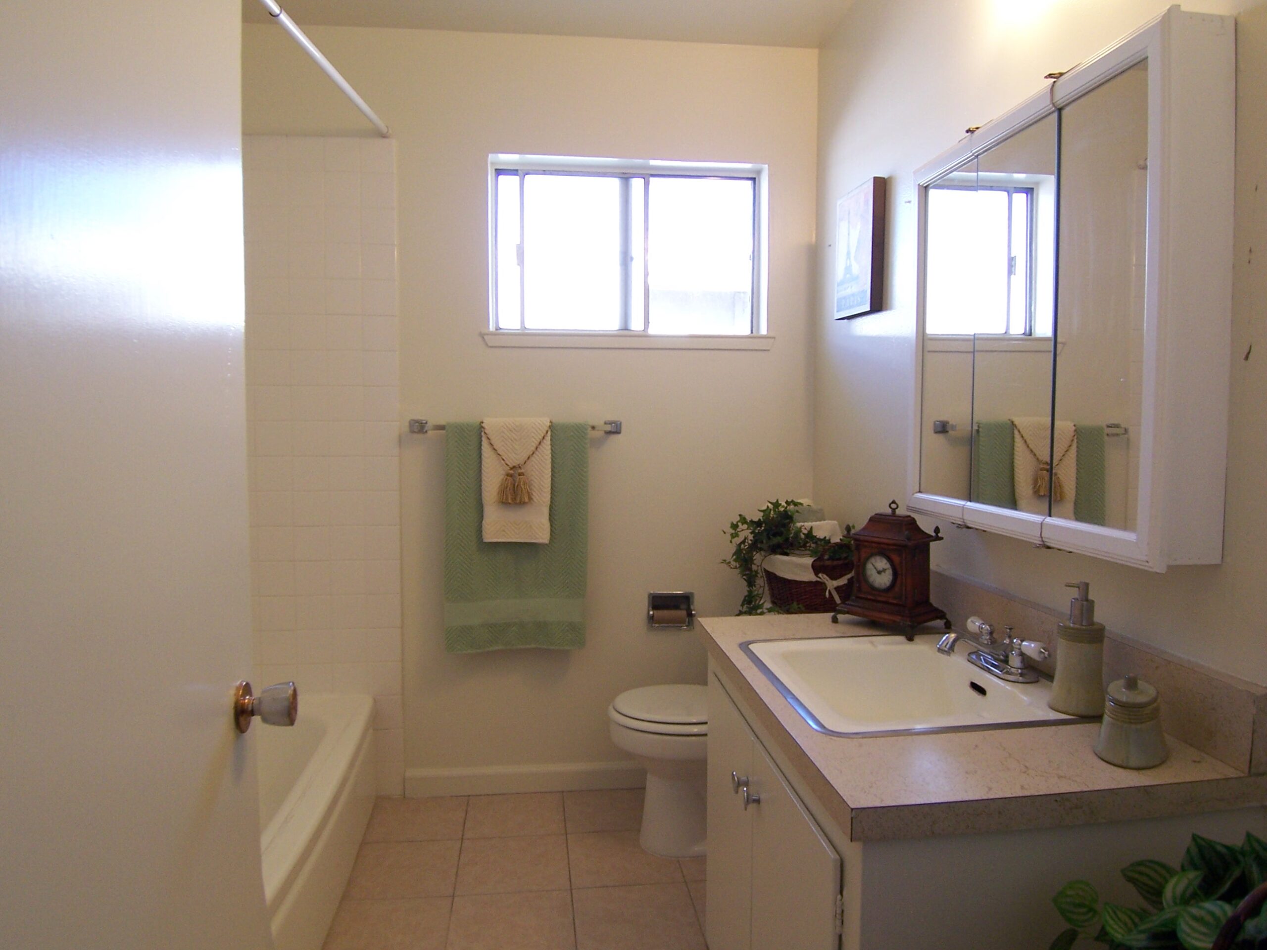 A bathroom with white tile and green towels.